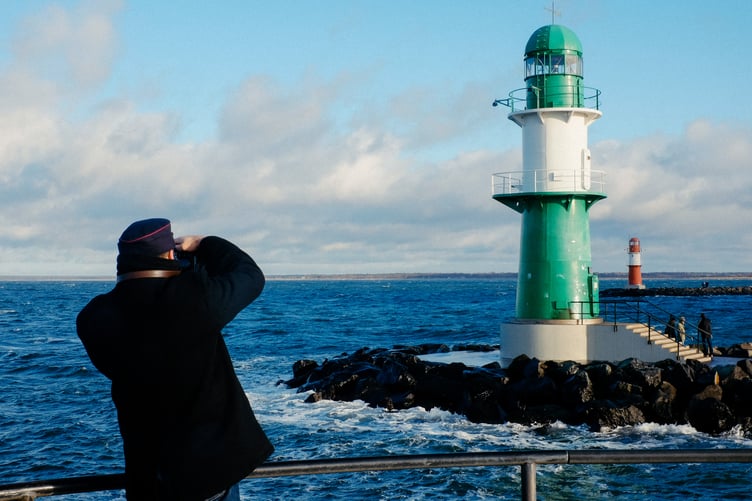 Mann fotografiert Leuchtturm an Küste